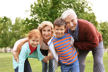 Happy senior couple with grandchildren in park