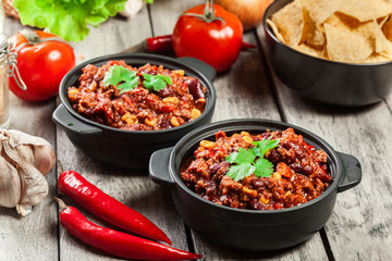 Bowls of hot chili con carne with ground beef, beans, tomatoes and corn