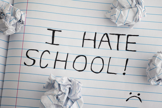 I Hate School. Phrase I Hate School on notebook sheet with some crumpled paper balls on it