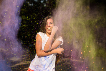 Smiling asian woman with long hair posing in a cloud of Holi paint