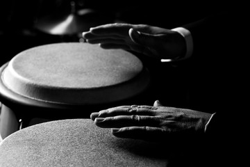 Hands of a musician playing on bongs closeup in black and white tones