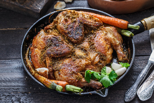 Whole roast chicken in an iron pan, rustic style, close view