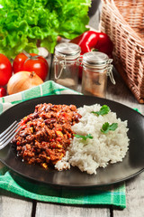 Hot chili con carne with ground beef, beans, tomatoes and corn served with rice