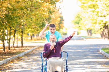 Young caregiver walking with senior man in park