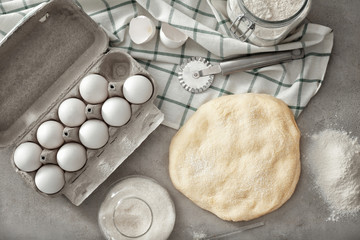 Composition with raw flaky dough and carton of eggs on table