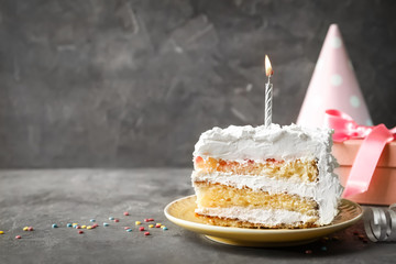 Piece of birthday cake with candle on table