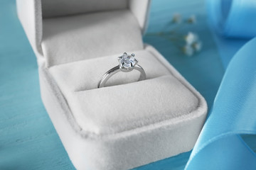 Box with luxury engagement ring on color background, closeup