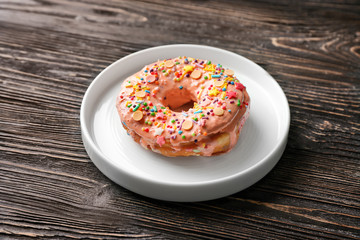 Plate with tasty donut on wooden table