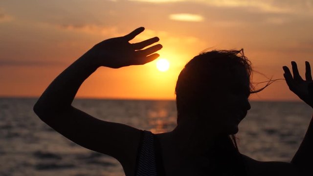 Silhouette of young happy woman have fun listening music in headphones on the beach at amazing sunset in slow motion. 1920x1080
