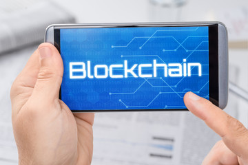 Smartphone mit dem Text Blockchain auf dem Display