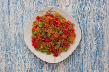 Candied pineapple in a white plate on a white blue wooden table