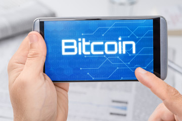 Smartphone mit dem Text Bitcoin auf dem Display
