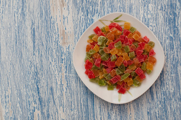 Candied pineapple in a white plate on a white blue wooden table