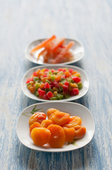 Different candied fruits in plates on a wooden table