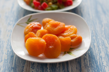 dried apricots in a white dish on a wooden background