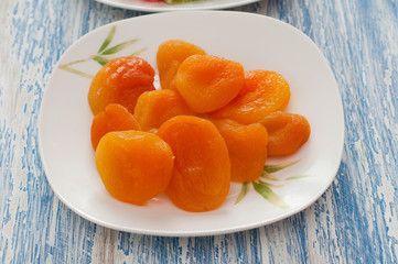 dried apricots in a white dish on a wooden background