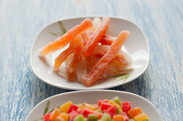 Candied papaya in a white plate on a wooden background