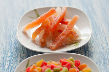 Candied papaya in a white plate on a wooden background