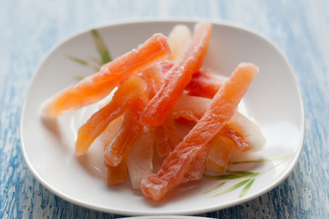Candied papaya in a white plate on a wooden background