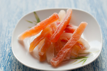 Candied papaya in a white plate on a wooden background