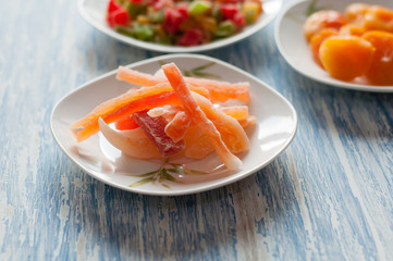 Candied papaya in a white dish on a wooden table