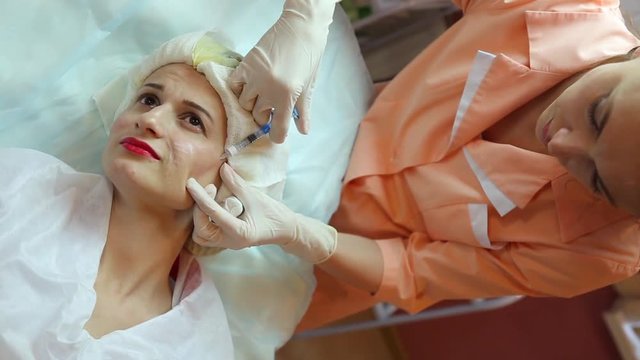 beautician does a rejuvenating subcutaneous injection to woman patient