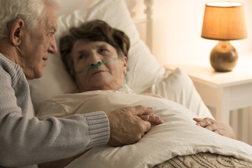 Elderly man supporting sick wife