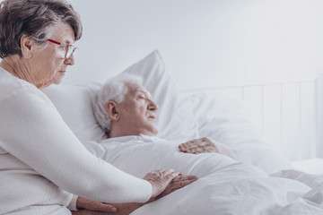 Elderly woman supporting sick husband