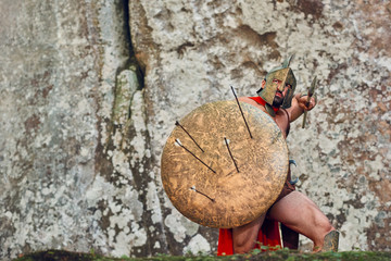 Shot of a brave Spartan protecting himself with a shield holding a spear fighting his archer enemy...