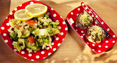 mushroom head filled with cheese baked and green salad. On red dotted plates