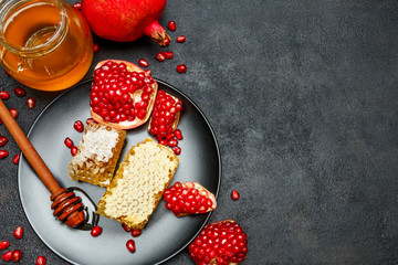 Pomegranate and honeycomb close-up on dark concrete background