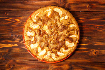 Freshly baked apple pie on a rustic background of dark wood.