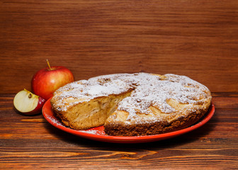 Fresh apples and a piece of apple pie sprinkled with powdered su