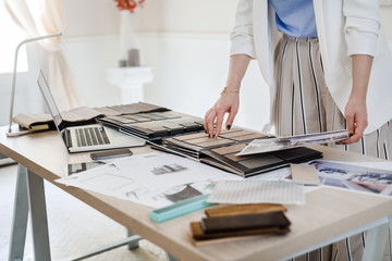 Hands of unrecognisable woman interior designer working with material palette at her office.