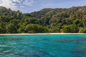 Small touristic boat on the scenic wild beach against the background of magnificent tropical vegetation , Redang island, Malaysia