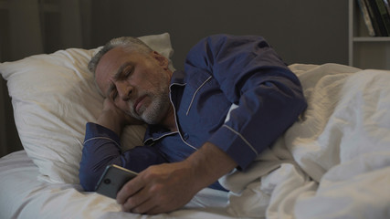 Fototapeta premium Addicted to smartphone retired man scrolling application instead of sleeping