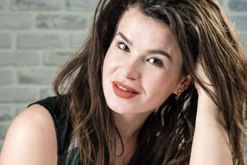 Portrait of a beautiful woman on the background of a light brick wall