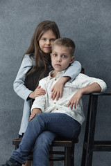 A portrait of little girl and a boy on the gray background