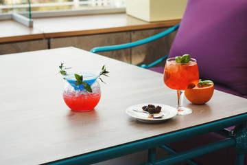 Modern serving of italian spritz and blue lagoon with orange slices