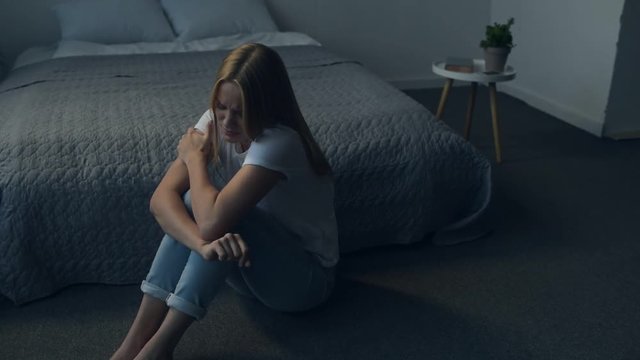 Unfair world. Full length of young girl feeling depressed while sitting on the floor and covering her head with hands