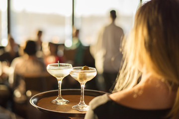 Rear view of waitress holding drinks in tray at restaurant
