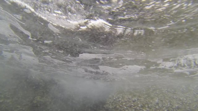 Waves beating on rocks filmed by underwater camera moved by waves oscillation.

