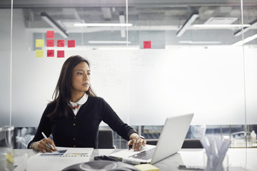 Serious businesswoman using laptop computer on desk in office