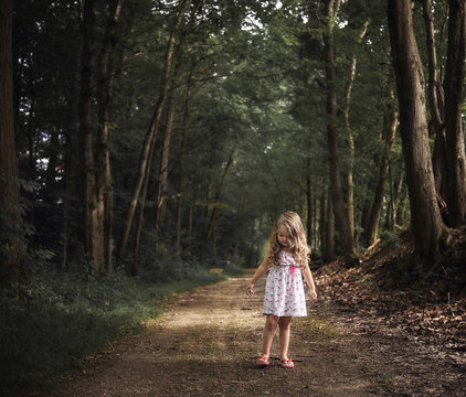 Girl standing on dirt road in forest