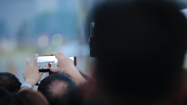 Tourists takes pictures with a smart phone, a famous landmark and a popular tourist attraction in China, view from back. Hands of people take photos on the street
