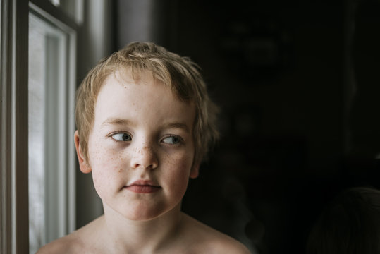 Close Up Of Boy Looking Through Sideways Glance In Darkroom