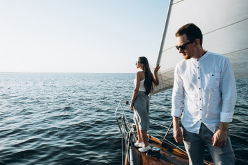 Young guy in sunglasses rest on the yacht and swim by the sea