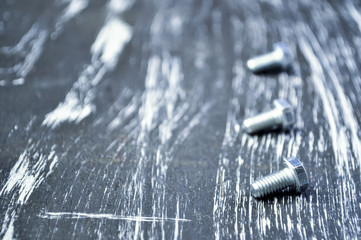 Nuts for repairs lying on a wooden table. Iron nuts and screws f