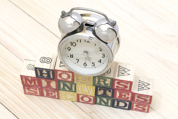 Clock with wood cubes on wooden table words hours,minutes,seconds