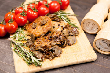 Close up top view on pork steak with grilled mushrooms on wooden board. Delicious healthy food